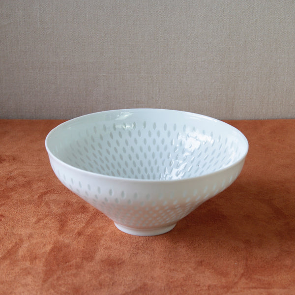 Top down looking into a white porcelain bowl by Friedl Holzer-Kjellberg featuring a rice grain design, representing midcentury Nordic design.