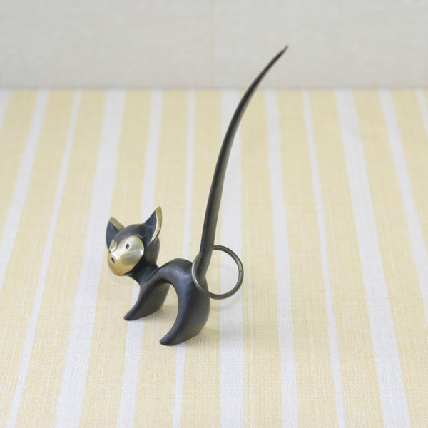 A Walter Bosse brass cat pretzel holder from the 1950s, influenced by the sleek style of Hagenauer. This collectible piece was crafted in Vienna, adding charm to any collection of mid-century metalwork.