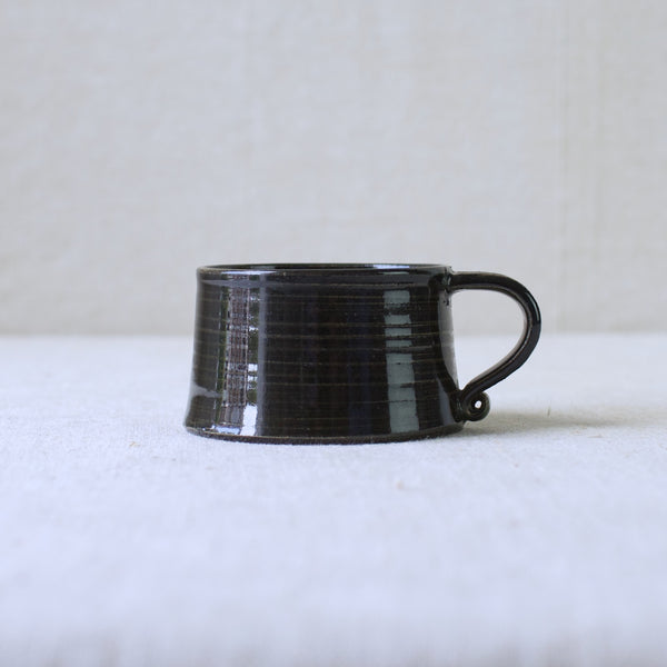 Profile view of a Kaarina Aho stoneware cup designed for Arabia Finland in 1957. Hand-thrown, hand-glazed, and beautifully organic. The design shows the influence of Kaj Franck.