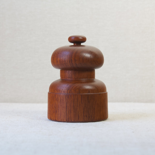 Straight on shot of a dark nut brown coloured teak wood pepper mill designed by Jens H. Quistgaard.  This design is nicknamed "mushroom" and is one of around 60 pepper mills that JHQ designed for Dansk Design from the late-1950s.