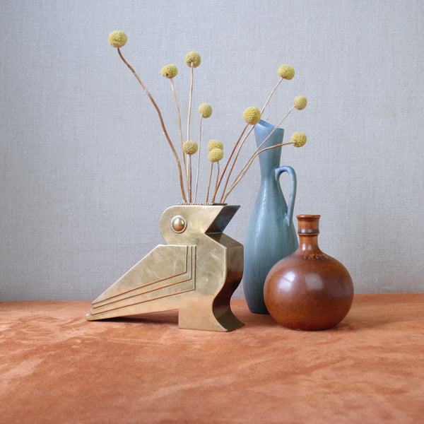 Vintage Bauhaus-inspired brass bird sculpture with a bud vase, showcasing Art Deco design from Britain circa 1930. Ideal for collectors. Photo also features Scandinavian ceramics.