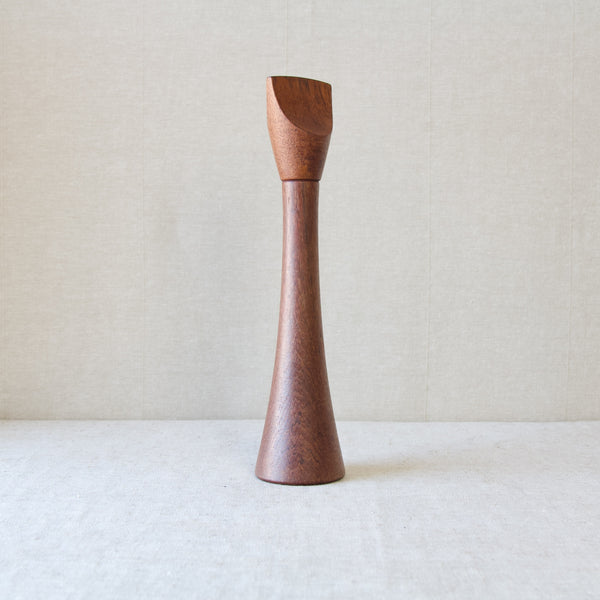 Straight on shot of a tall reddish brown coloured teak wood pepper mill, design by Jens H. Quistgaard for Dansk Designs. Available for worldwide delivery to Japan, China, Singapore, Taiwan.