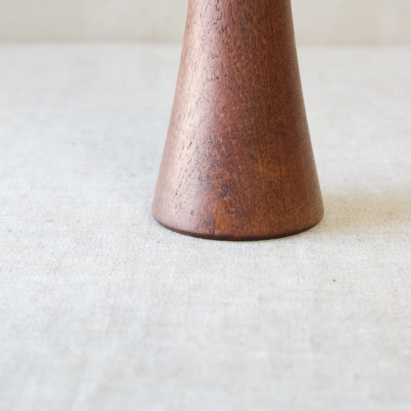 Zoomed in image looking at the base of a cylindrical turned teakwood pepper mill. This mill is similar to the classic exaggerated mills used in Italian restaurants but this design is by leading Danish designer Jens Harald Quistgaard.