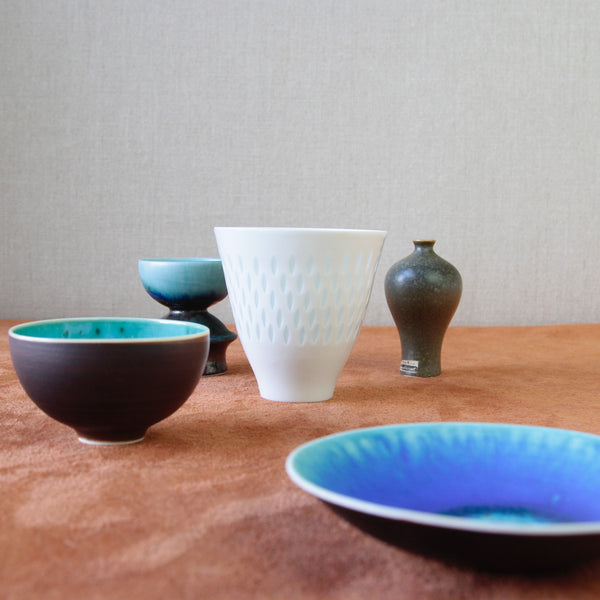 Group shot of five pieces of vintage Nordic design. Centre is a small porcelain vase by Friedl Holzer-Kjellberg, showcasing exquisite rice grain pattern that reflects the elegance of midcentury Finnish design. For sale at Art & Utility in London.