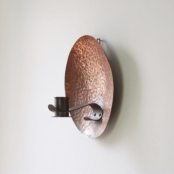 Hammered copper backplate wall sconce, an early 20th-century British arts & crafts piece.