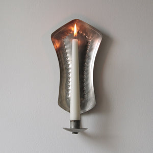 Head on shot of a silver coloured pewter wall sconce for a dinner candle. This classically inspired Finnish design dates from the 1940s and was influenced by the work of Paavo Tynell.