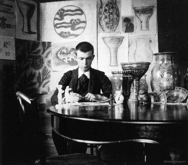 Early photo of Svend Hammershøi sat surrounded by Danish ceramics and drawings of ceramic designs.