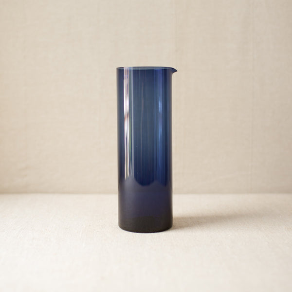 Rare Kaj Franck blue glass pitcher from 1954 featuring a minimalist modernist design. A collectible piece that exemplifies Scandinavian mid-century style.