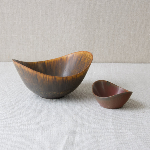 Two Gunnar Nylund bowls with flared rim, one ARO with ochre glaze, one Rörstrand miniature in brick red. Collectable vintage designs from Sweden.