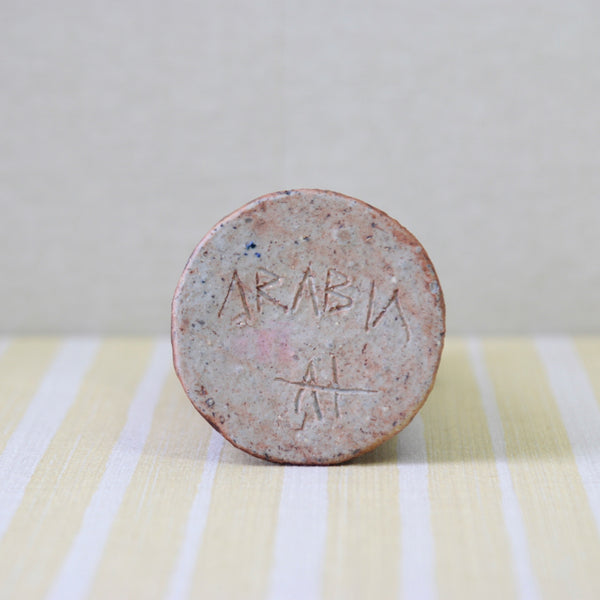 Underside base of an iron glaze chamotte clay vase by Annikki Hovisaari, created in 1970 for Arabia Finland. Hand inscribed signature reads ARABIA AH. AH is the monogram for Annikki Hovisaari. 

