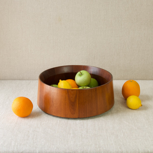 A large staved teak fruit bowl, or salad bowl containing oranges, apples and lemons. The mid-century modern Scandinavian design is by Jens Quistgaard IHQ for Dansk Designs, Denmark