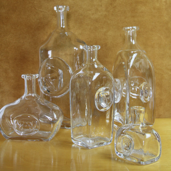 Group shot of 5 clear glass bottles designed by eric hoglund for boda in the 1960s