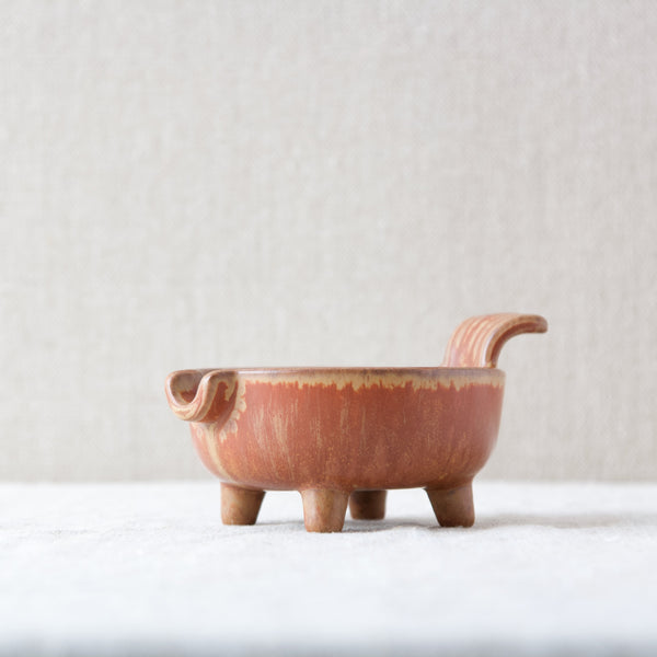 A footed dish with a fluted handle designed by Gunnar Nylund for Rorstrand. This is a particularly quirky example of Nylund's design for functional household items.