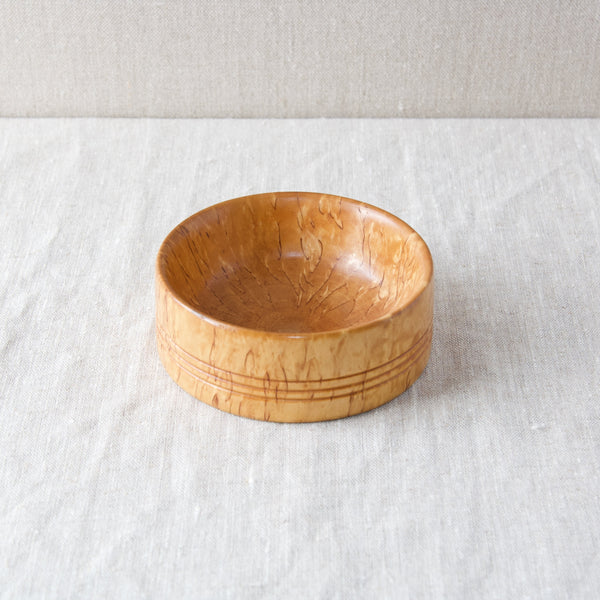 A karelian birch bowl. Rather than an actual species, Karelian birch is a variant of silver birch with a a genetic defect that creates an ununsual grain figure.  Namely, the trees’ annual rings are oriented incorrectly, which gives the wood a fiery, sunburst, appearance. 