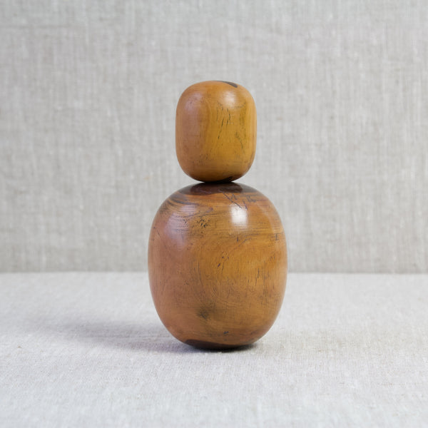 A small wooden egg shaped bobbin stood on top of a larger lignum vitae plumber's bobbin. These antique tools are fantastic display pieces and desk ornaments.