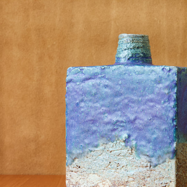 Detail of a square bottle shaped Annikki Hovisaari vase. The clay has intentionally been left with a rough texture which makes the vase appear to have been hewn or carved from a block of stone.