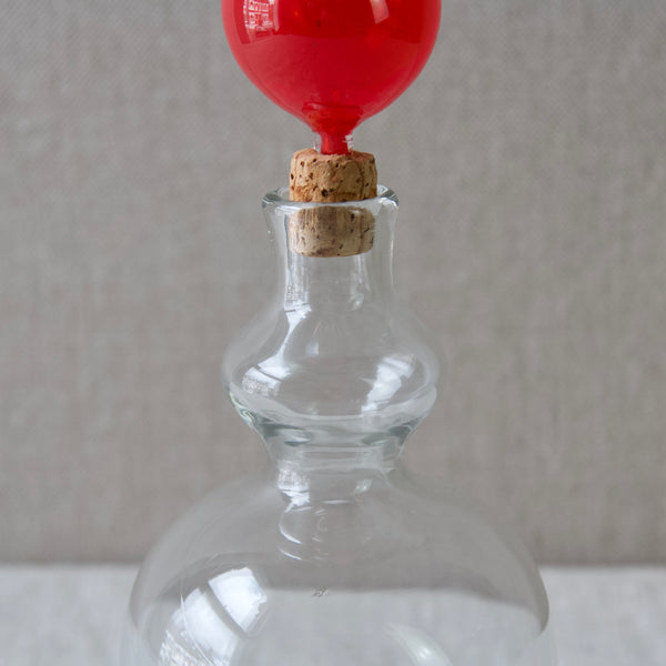 Close up image of turned neck of clear glass bottle decanter with red stopper designed by Kaj Franck, 1950s 