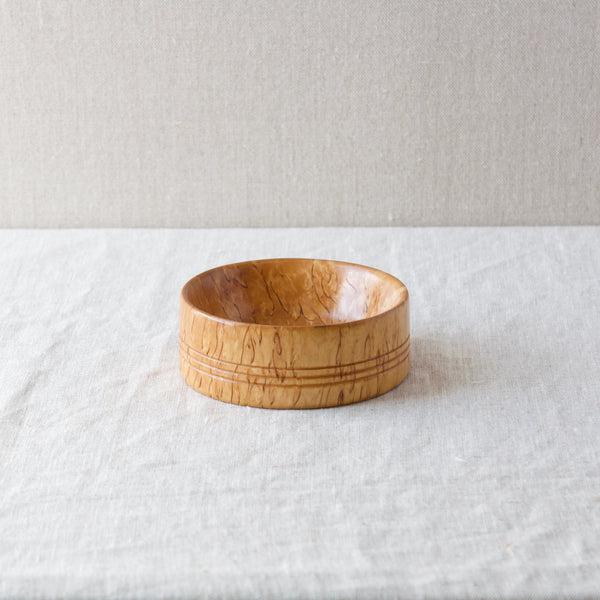 An angled shot showing inside and out of a blonde Karelian birch bowl that was handmade by a craftsperson in Sweden in the 1960s.