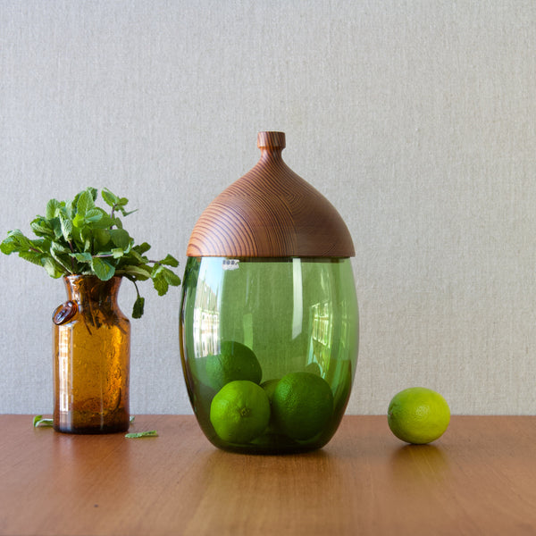 A still life mood image showing vintage Erik Hoglund storage jar and vase with limes and mint