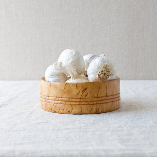 A pile of garlic bulbs inside of a Karelian birch (aka Curly birch) bowl, handmade in Sweden in the mid-twentieth century.
