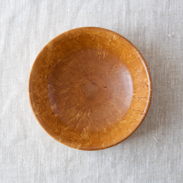 The view into a Karelian birch bowl that boasts a sunburst flame like grain. This useful object, great for storing small items, was handmade in Scandinavian by a craftsman in the 1960s.